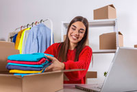 Woman packing folded clothes into box.
