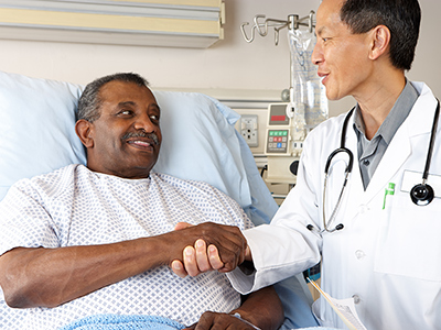 Man in hospital bed visiting with a doctor