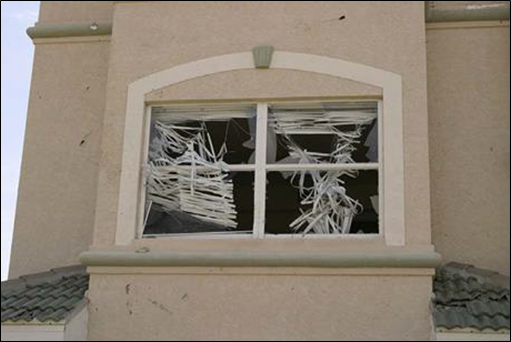 Window glass broken by windborne debris.