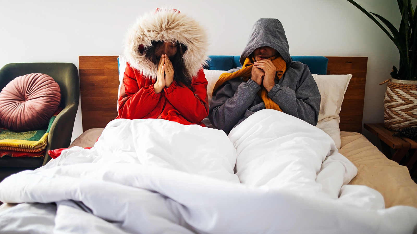 A couple wearing winter coats in bed 