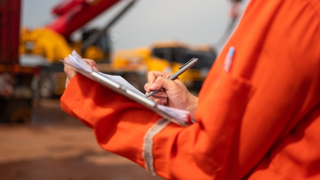 Crane inspector with a clipboard checklist